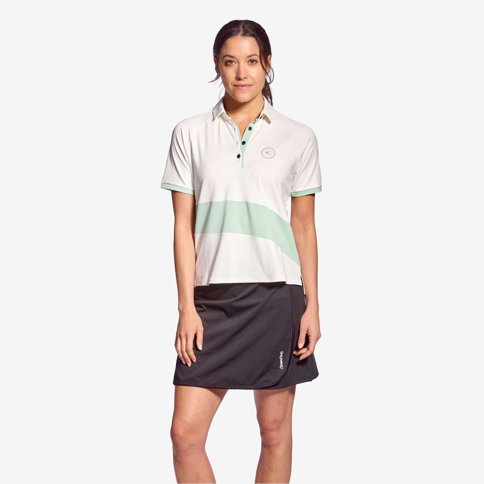 Woman wearing the Kymira Women’s Strike Polo — lightweight infrared golf polo designed for focus, comfort, and freedom of movement. Green/Light Grey